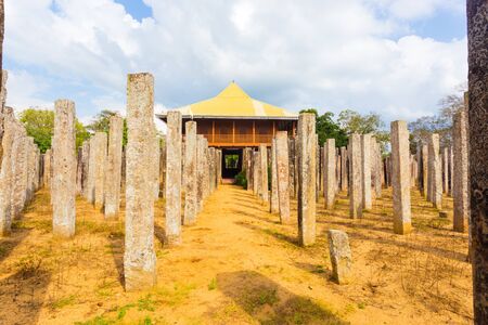Stone pillars of the ruins of Brazen Palace or Lovamahapaya lead into a modern structure on a blue sky day in ancient Anuradhapura capitol in Sri Lanka. Horizontalのeditorial素材