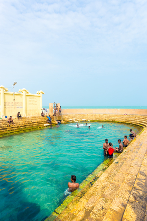 Keerimalai, Sri Lanka - February 5, 2015:  Sri Lankan swimmers enjoy the sacred Keerimalai Hot Springs with an ocean view, a tourist attraction on the northern coast of Jaffna. Verticalのeditorial素材