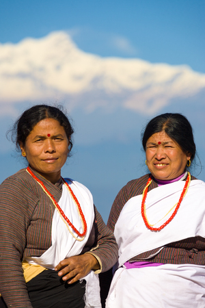 Bandipur, Nepal - December 17, 2007: Two beautifully dressed ethnic villagers dressed in clean traditional clothes stand in front of snow-capped Himalayan mountainsのeditorial素材