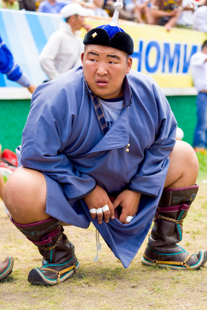 Ulaanbaatar, Mongolia - June 11, 2007: Lone large heavyweight wrestler waiting at field level in a squat position inside the National Sports Stadium at the Naadam Festival wrestling eventのeditorial素材