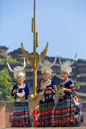 Xijiang, China - September 15, 2007: Three Miao women wearing full traditional festival regalia with silver horn headdress at town square in Xijiang ethnic minority Miao village, Guizhou, Chinaのeditorial素材