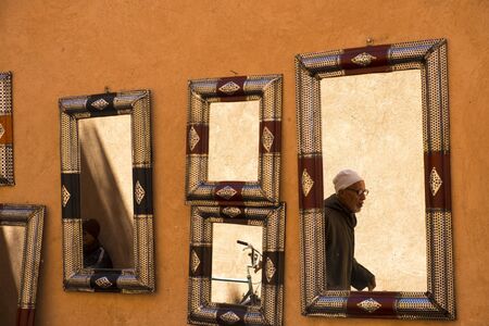 Marrakech, Morocco - March 27, 2018: Mirror reflection of man walking in narrow alley in the souq...
