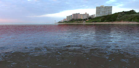 water. seashore at dawn. A lighthouse is visible in the distance. city buildings. 3d rendering.の写真素材
