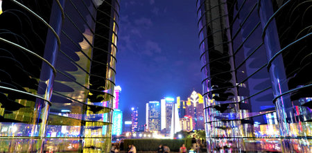 Blurred people in the yard of the contemporary apartment building at night with illuminated city on the backspace. 3d rendering.の写真素材