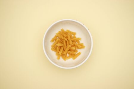Fusilli in white dish on yellow backgroundの写真素材