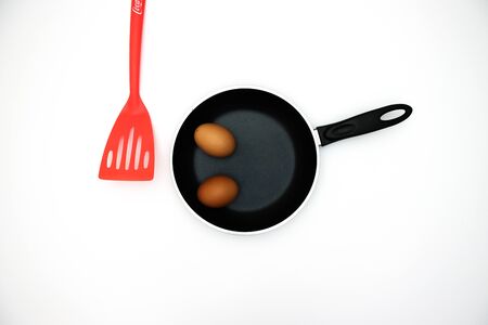 Spoon and pan with two eggs for breakfast