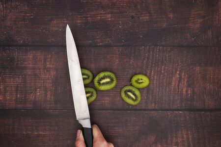 Knife and cut kiwi on wooden tableの写真素材
