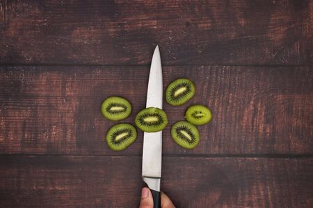 Knife and cut kiwi on wooden table