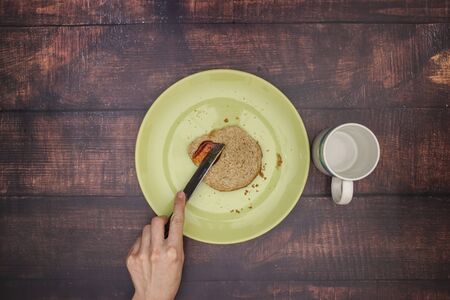 Putting jam on the fresh bread for breakfastの写真素材