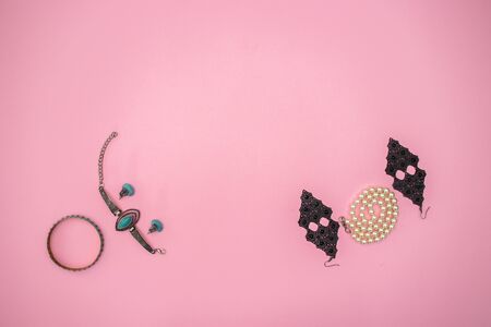 Woman's accessories and jewelry on pink background