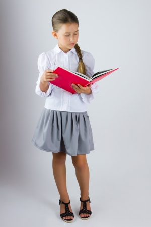 Smart schoolgirl reading a bookの写真素材
