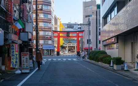 A snapshot of a typical weekday afternoon in the Tokyo urban neighborhood of Higshi-Ueno in Taito Ward, featuring a striking vermilion torii gate leading to Shitaya shrine.の写真素材