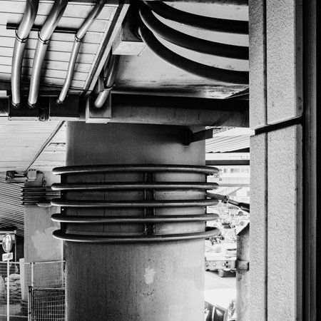 I captured this high-contrast monochrome shot of the underside of a pedestrian overpass, showcasing an intricate mix of lines, angles, and contrasting round and flat shapes.の写真素材