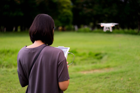 Women operating the drone by remote control in the park.の写真素材