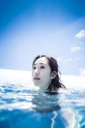 Beautiful asian woman swimming in the pool with blue sky backgroundの素材