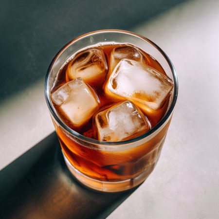 Cola with ice cubes in a glass on a dark background, top viewの素材