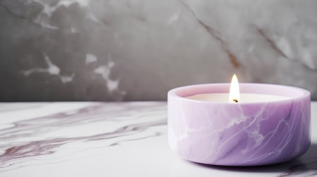 Burning candle on a marble table with a stone wall in the backgroundの素材