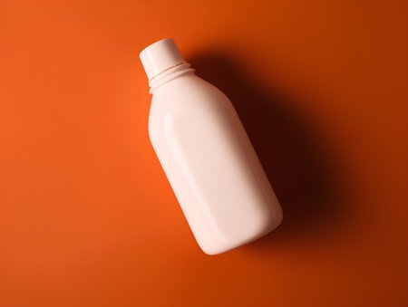 Blank white plastic bottle on orange background. Minimal style.の素材