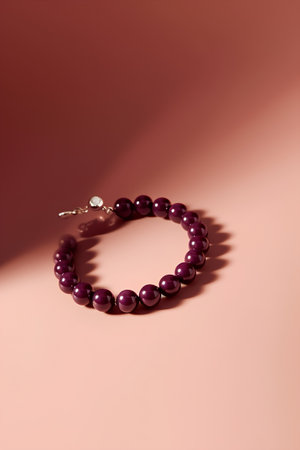 Bracelet made of natural purple beads on a pink background.の素材