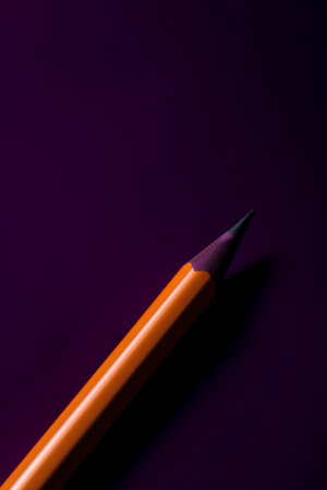 Orange pencil on a purple background. Minimal concept. Top view.の素材