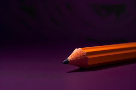 Orange pencil on a dark purple background. Back to school concept.の素材
