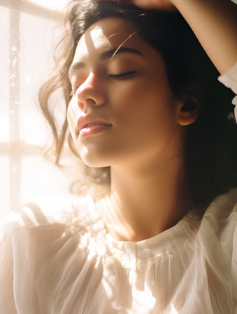 Beautiful young woman with closed eyes in morning light at window.の素材