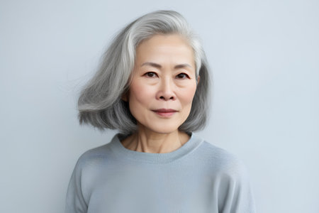 Portrait of beautiful asian senior woman with grey hair on grey backgroundの素材