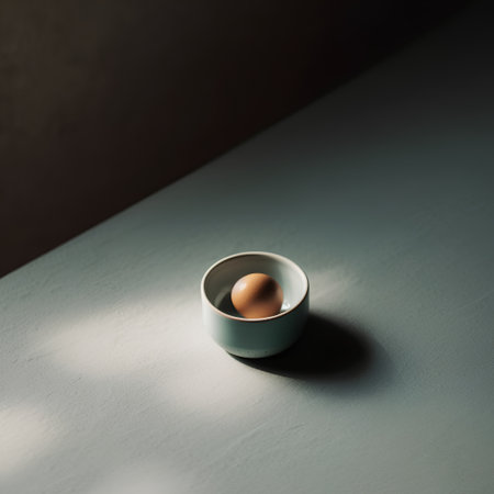 One egg in a blue egg cup on a dark background with a shadowの素材