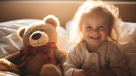 Little cute girl playing with teddy bear in bed at home.の素材