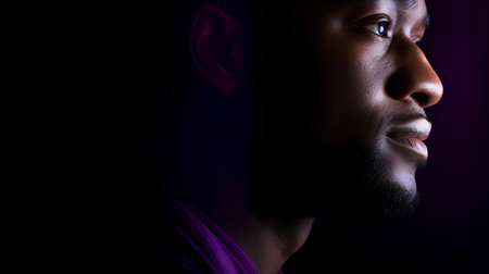 Close-up portrait of a young African-American man on a dark background.の素材