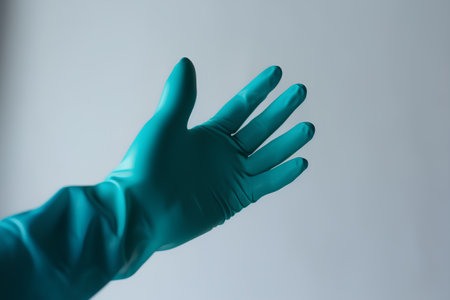 Hand in a medical glove on a gray background. Close-up.の素材