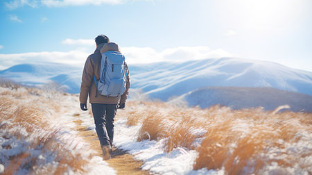 Man with backpack walking on snowy meadow. Travel and adventure conceptの素材