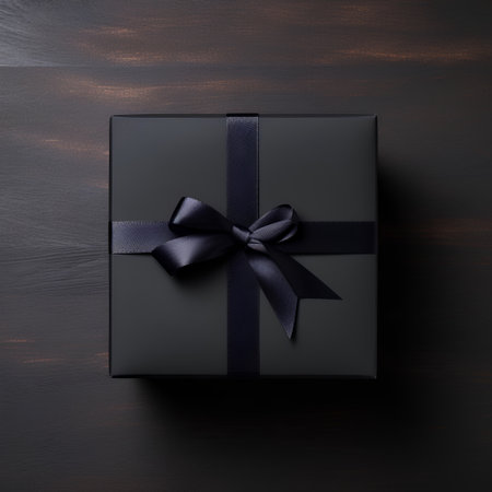 Black gift box with black bow on wooden background. Top view.の素材