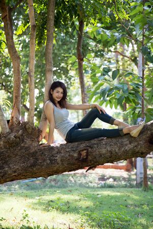 A girl is sitting on a tree of forest.の写真素材