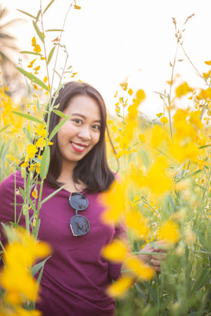 Young woman in a field of yellow flowersの写真素材