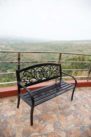 View of an bench on the top of the hill with the sky and the forest in the background on a sunny day,の写真素材