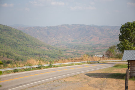 Country road down from the hill, mountain far away ahead, Thailand.