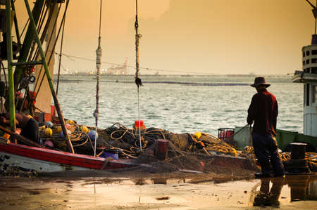 Fisherman working with sunset sky and sea background