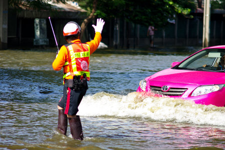 BANGKOK, THAILAND - NOV 7 : UNIDENTIFIED TRAFFIC POLICEMAN WORKING IN WATER FLOOD ON NOV 7, 2011 IN KAMPHAENG PHET INTERSECTION, BANGKOK, THAILAND. THE BIG FLOOD IN BANGKOKのeditorial素材