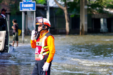 BANGKOK, THAILAND - NOV 7 : UNIDENTIFIED TRAFFIC POLICEMAN TALKING WITH WATER FLOOD ON NOV 7, 2011 IN KAMPHAENG PHET INTERSECTION, BANGKOK, THAILAND. THE BIG FLOOD IN BANGKOKのeditorial素材