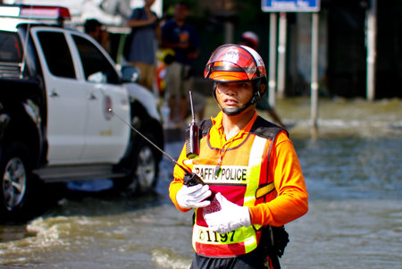 BANGKOK, THAILAND - NOV 7 : UNIDENTIFIED TRAFFIC POLICEMAN WORKING WITH WATER FLOOD ON NOV 7, 2011 IN KAMPHAENG PHET INTERSECTION, BANGKOK, THAILAND. THE BIG FLOOD IN BANGKOKのeditorial素材