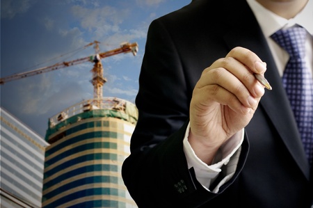 Businessman write on virtual board with construction site backgroundの写真素材