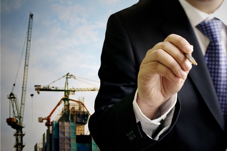 Businessman write on the air with construction site backgroundの写真素材