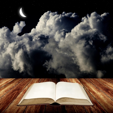 Open blak book on wooden table with night skyの写真素材