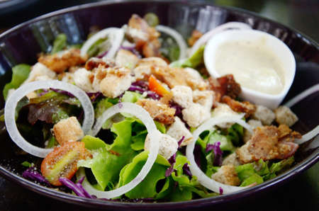 Salad with cream sauce in black dishの写真素材