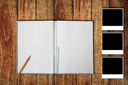 Notebook on wooden floor with photo framesの写真素材