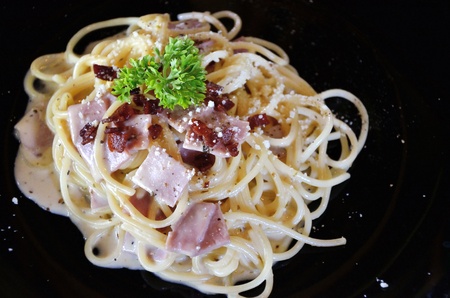 Spaghetti with ham isolated in black plateの写真素材