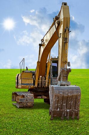 Track-type loader excavator machine on green grass fieldの写真素材