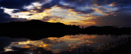 Panorama view of sunset sky with mountain silhouette and water in reservoir, Bang-pra, Chonburi, Thailandの写真素材