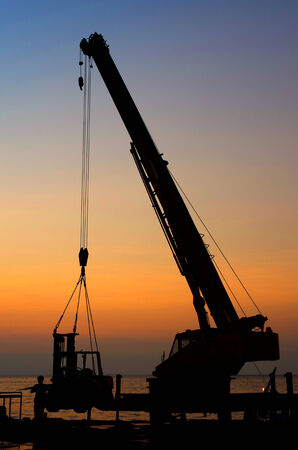 Silhouette crane working at port with sunset sky backgroundの写真素材